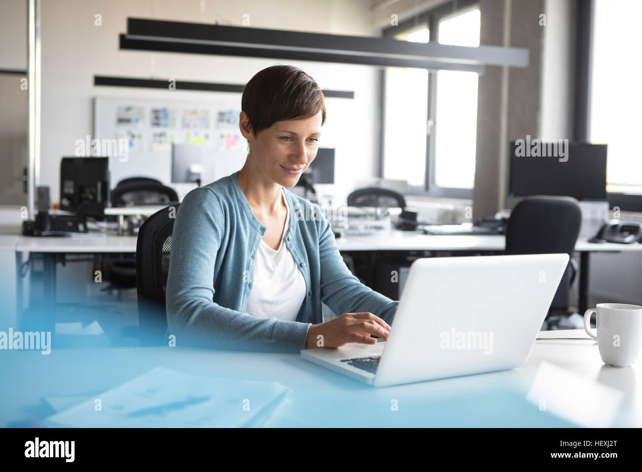 Businesswoman in office using laptop Stock Photo