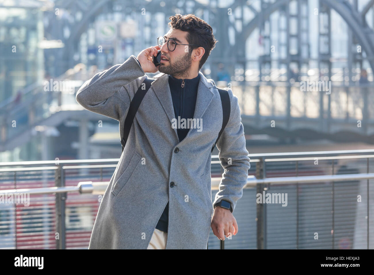 Businessman with baggage on the phone at train station Stock Photo