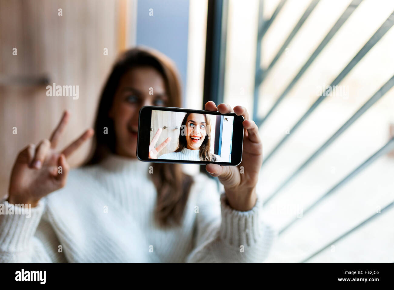 Playful young woman taking a selfie with cell phone Stock Photo - Alamy