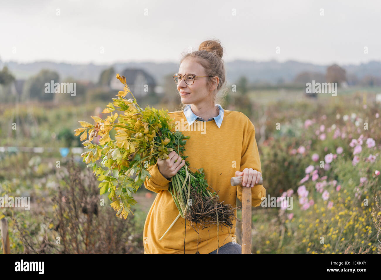 Young woman holding plant in cottage garden Stock Photo - Alamy