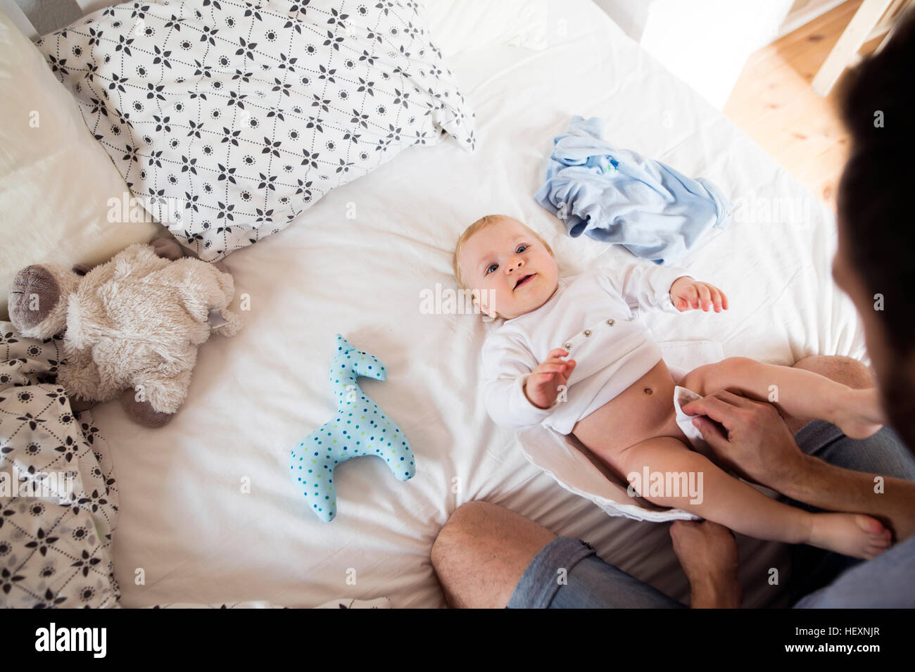 Father changing baby's diapers on bed Stock Photo Alamy