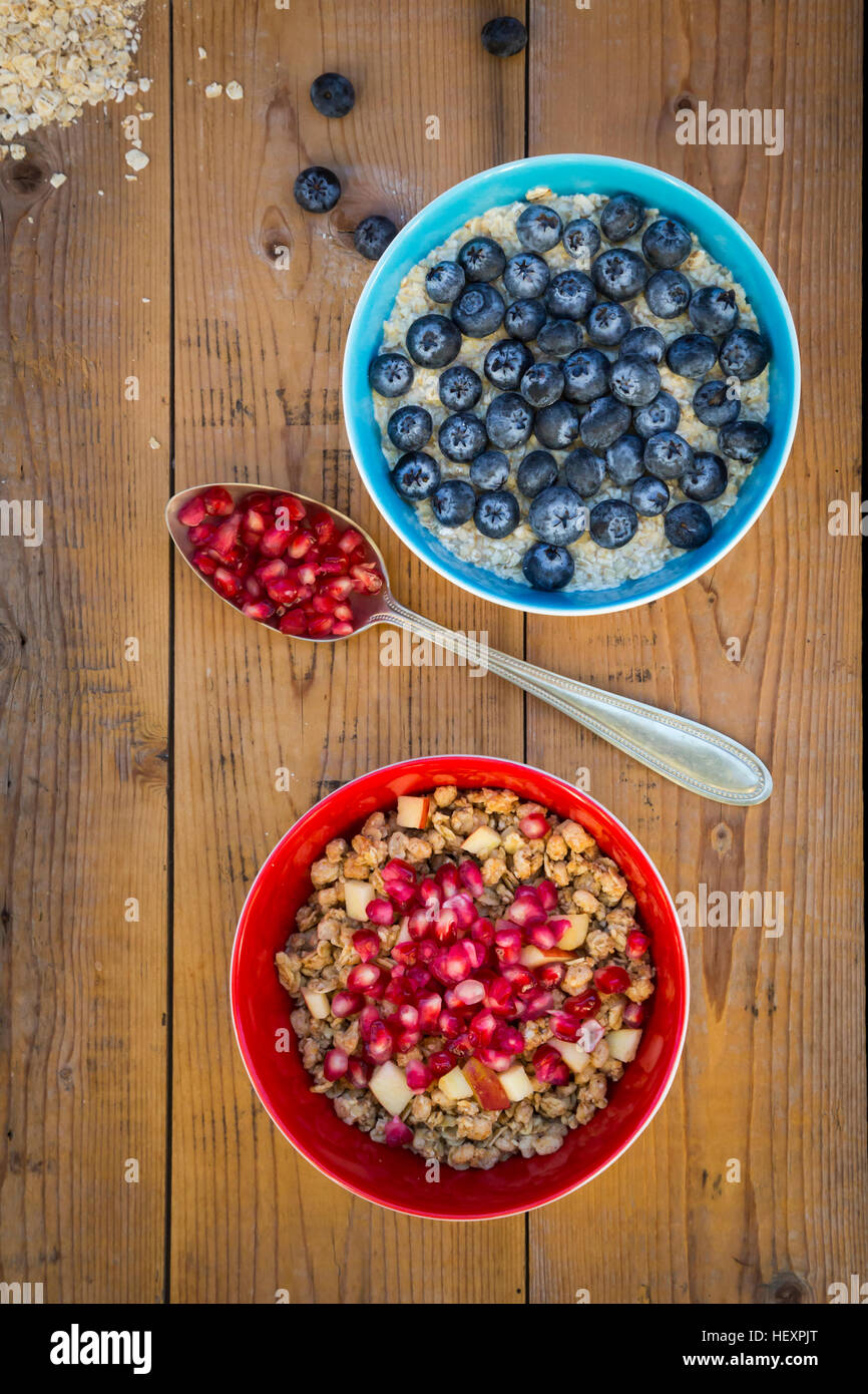 Bowl of overnight oats with blueberries and bowl of granola with pomegranate seed and red apple Stock Photo
