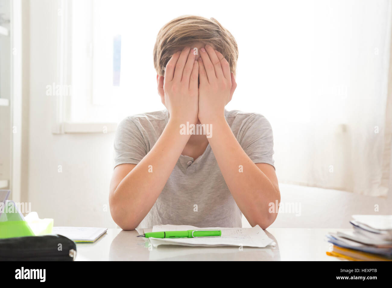 Boy doing homework covering his face Stock Photo - Alamy
