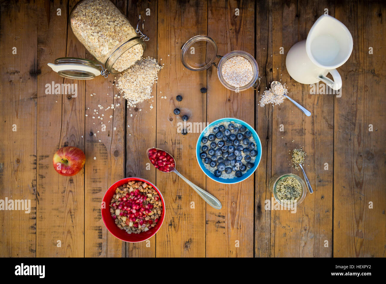 Bowl of overnight oats with blueberries and bowl of granola with pomegranate seed and red apple on wood Stock Photo