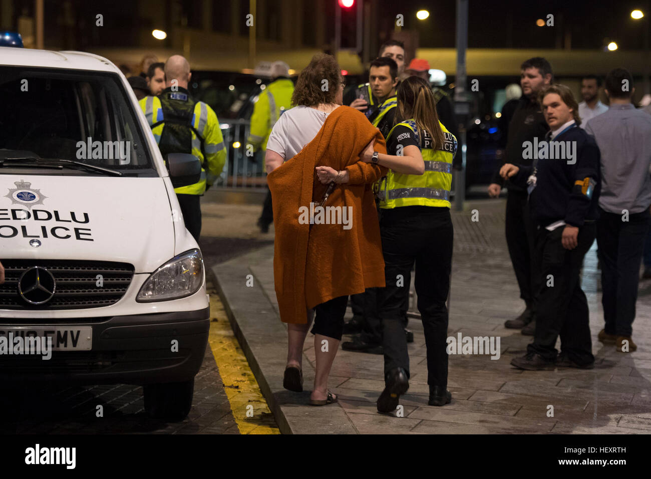 A police officer escorts a woman to a police van following an incident