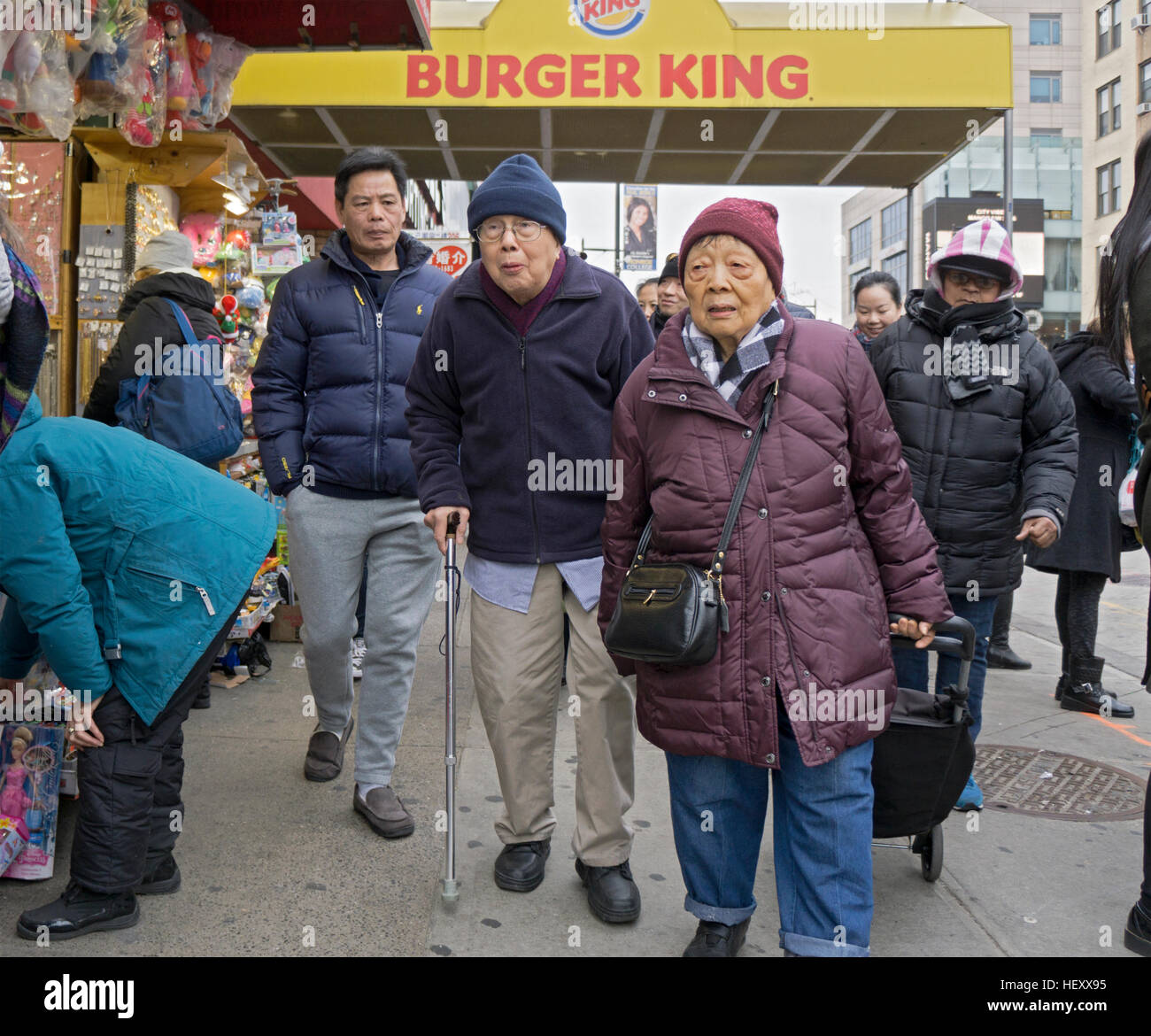 An elderly Chinese couple out shopping in the winter on Main Street in Chinatown, downtown Flushing, New York City Stock Photo