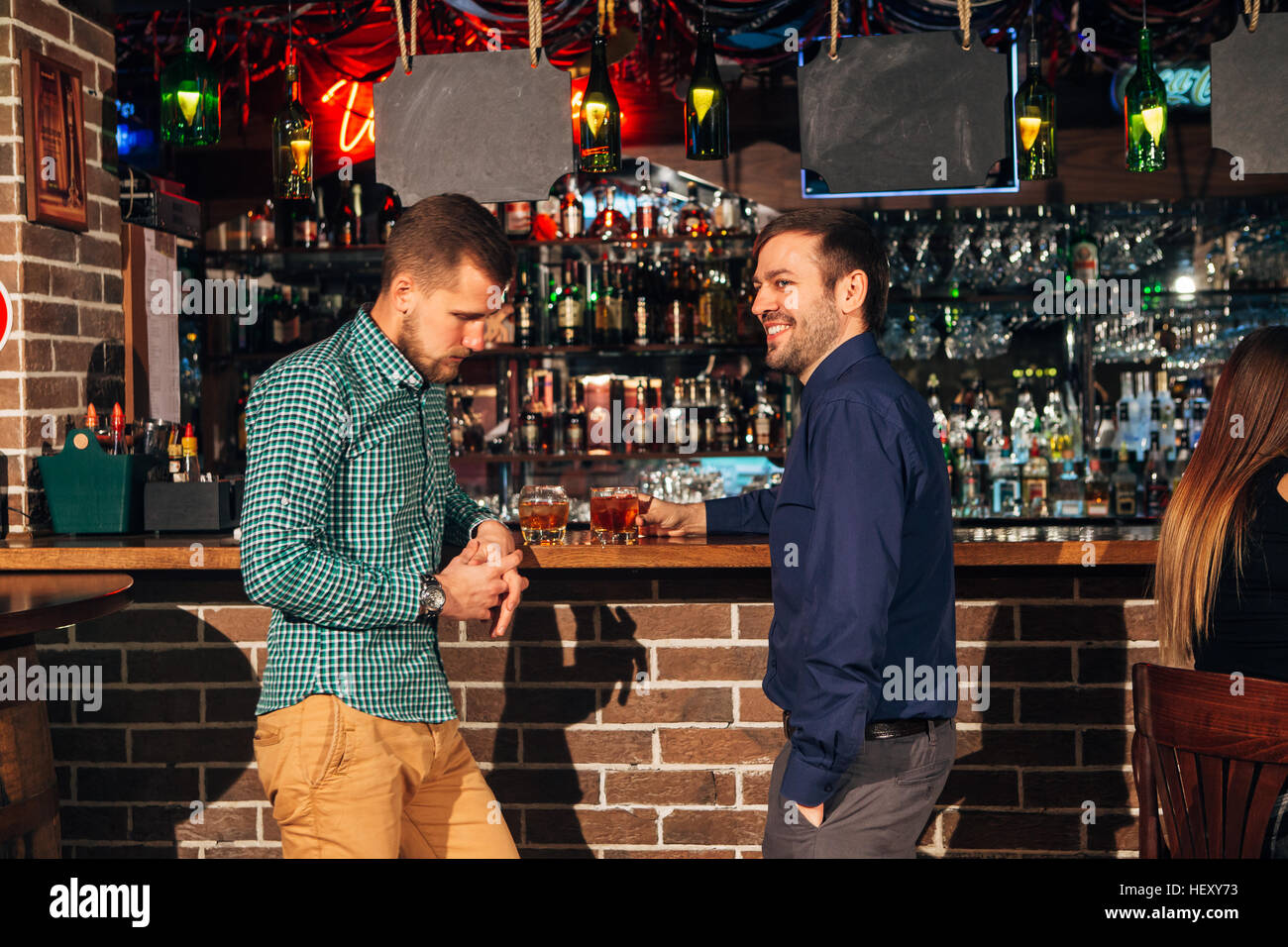 two young man talking at counter.  friends standing in bar and drinking whisky Stock Photo
