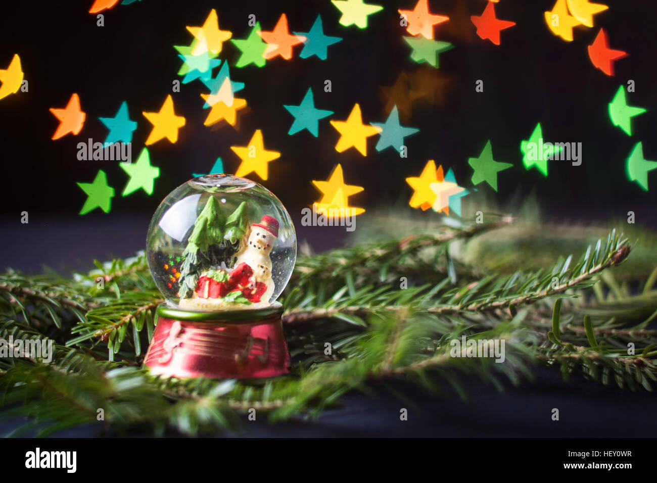 glass ball with snowman and star shaped bokeh in the background Stock Photo