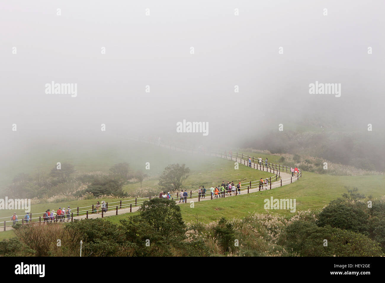 Long walking path leading all the way up the mountain obscured by heavy mist. Stock Photo
