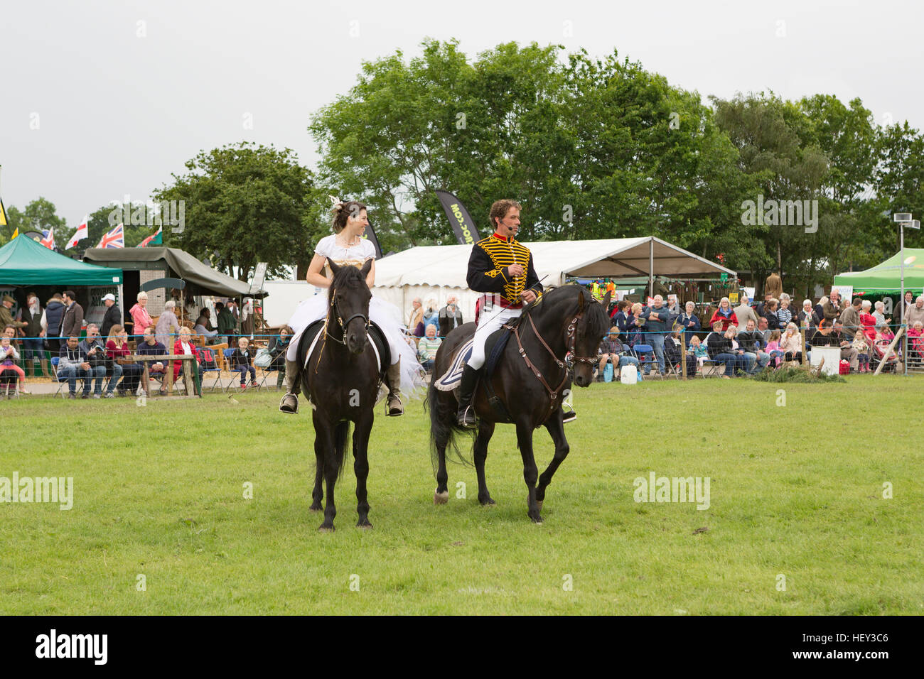 A man and women in costume ride horses at an exhibition event at the three counties show, Malvern, Worcestershire, England Stock Photo