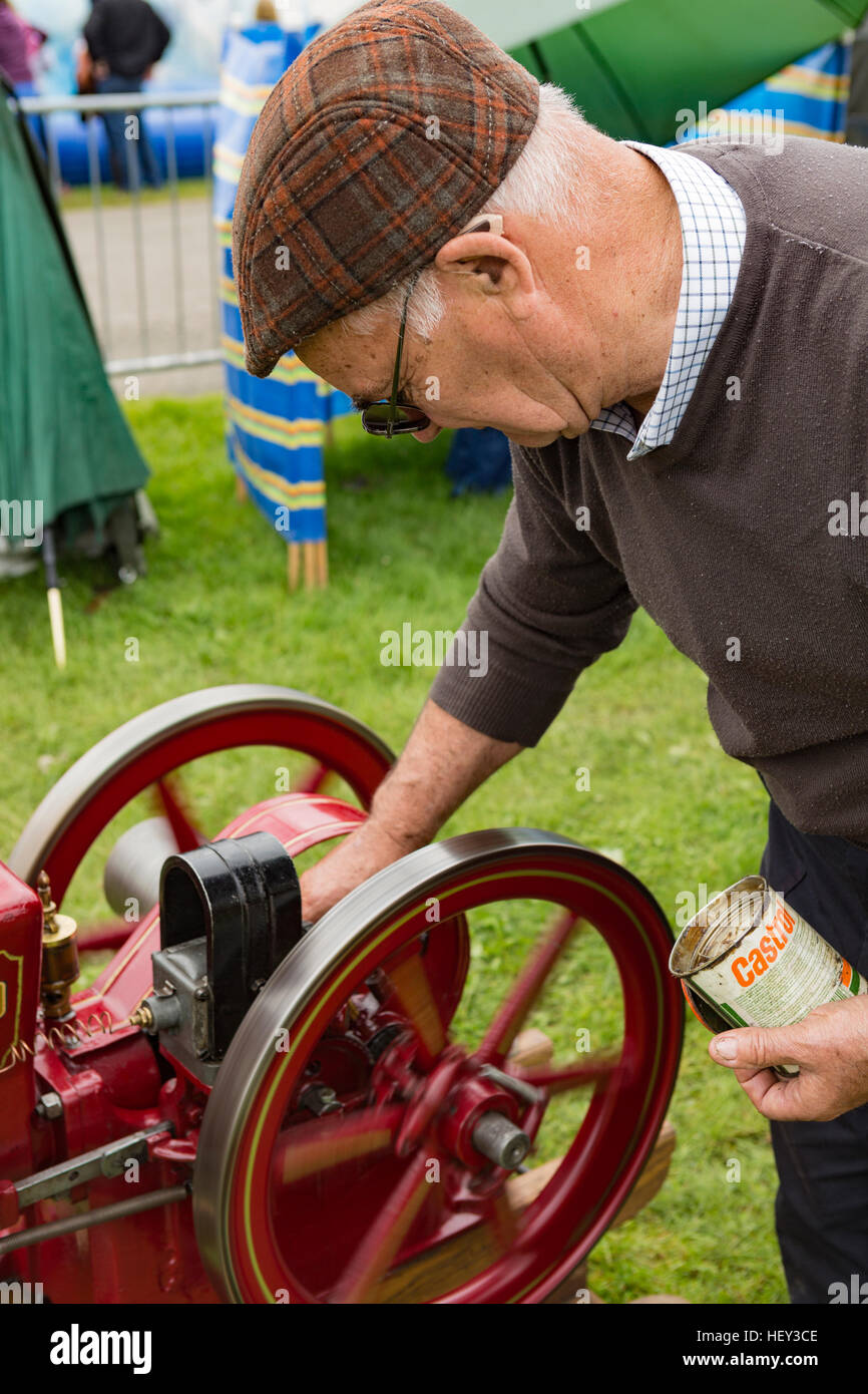 A man greases a Stationary Engine at a county show. Stock Photo