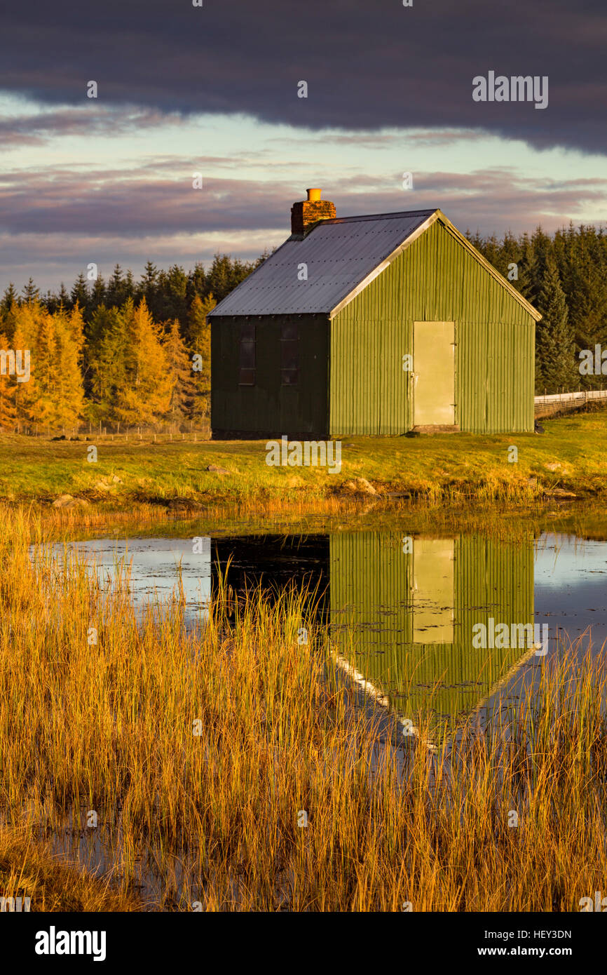 A bothy on the moorland above Kenmore is reflected in the reservoir at sunrise. Stock Photo