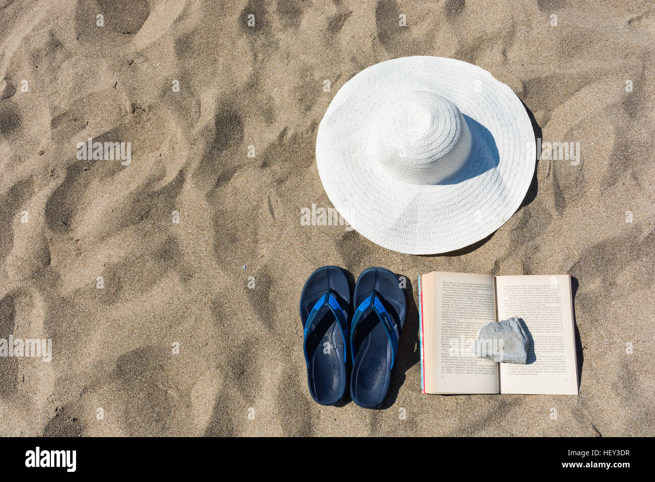 abstract and conceptual summer, holidays at the beach. With a white hat, blue slippers flip-flops and a book with a lid on it. Stock Photo