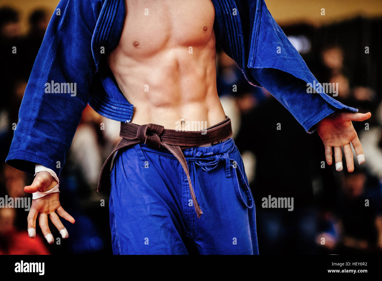 muscular body in sixpack of athlete judoka in blue kimono with brown belt Stock Photo