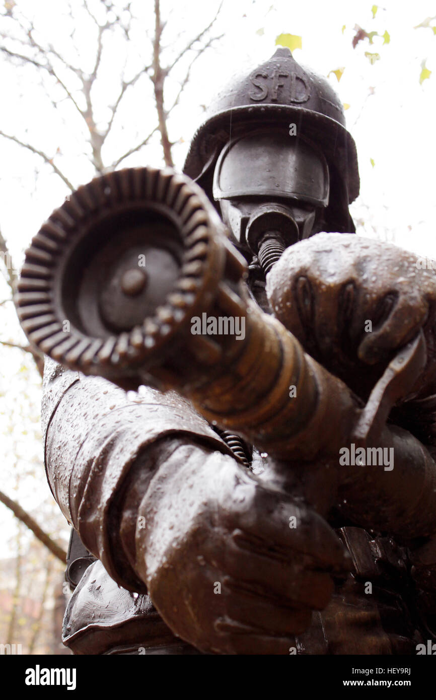 Statue of fireman with fire hose at the ready towards camera. Stock Photo