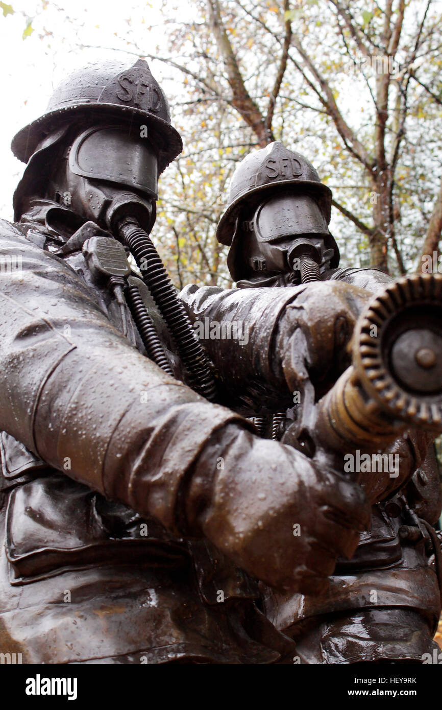 Statue of firemen with fire hose at the ready. Stock Photo