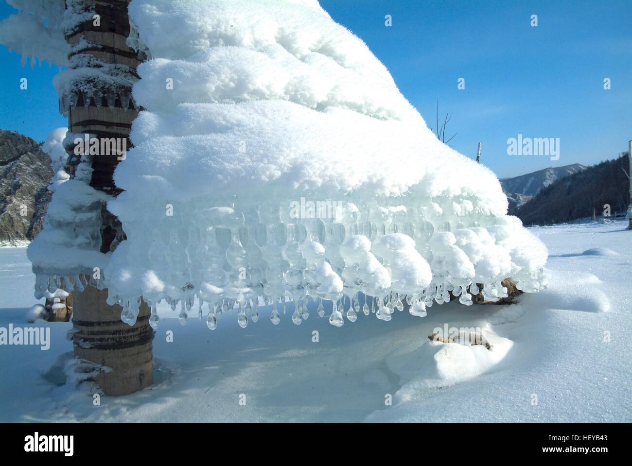 Strange form Icicles on tree on a background of mountains in the lake Stock Photo