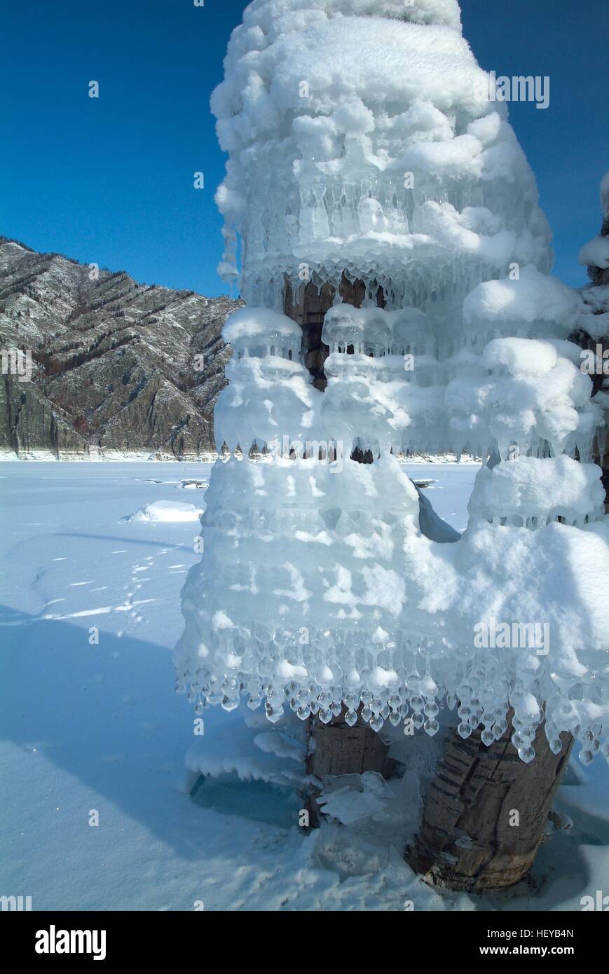 Strange form Icicles on tree on a background of mountains in the lake Stock Photo