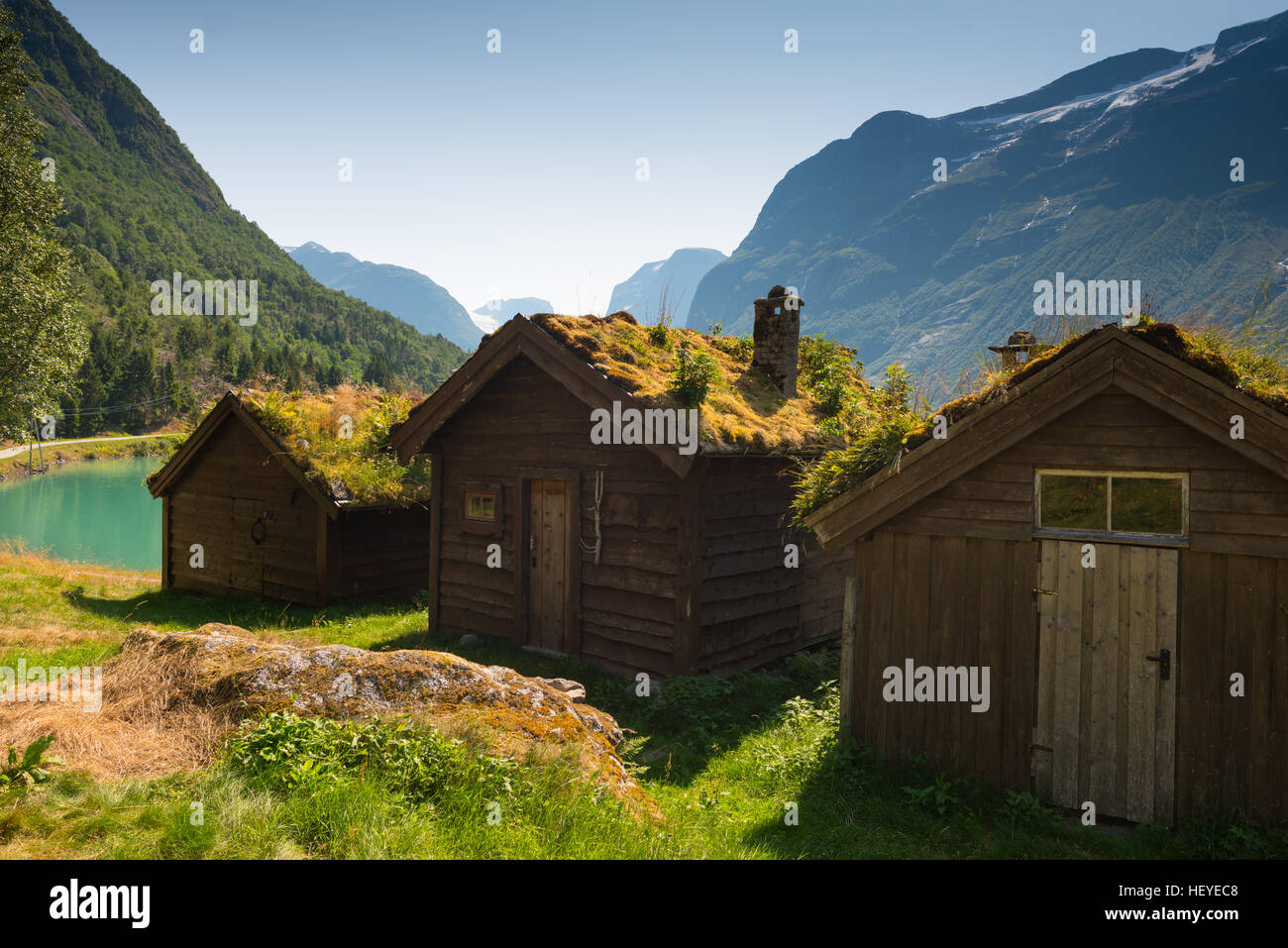 A view across Lovatnet Lake, a traditional Norwegian house sits in the foreground topped with sod roof Stock Photo