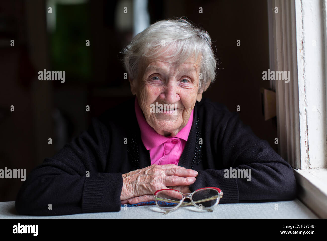 Old woman in her home, looking into the camera. Stock Photo