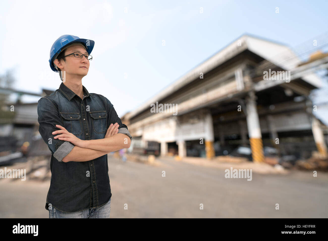 Asian engineer or technician looking upward, with clipping path, blur factory background, industry or engineering concept, young and handsome Stock Photo