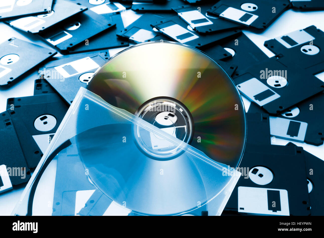 CD half out of its transparent holder in front of floppy disks Stock Photo
