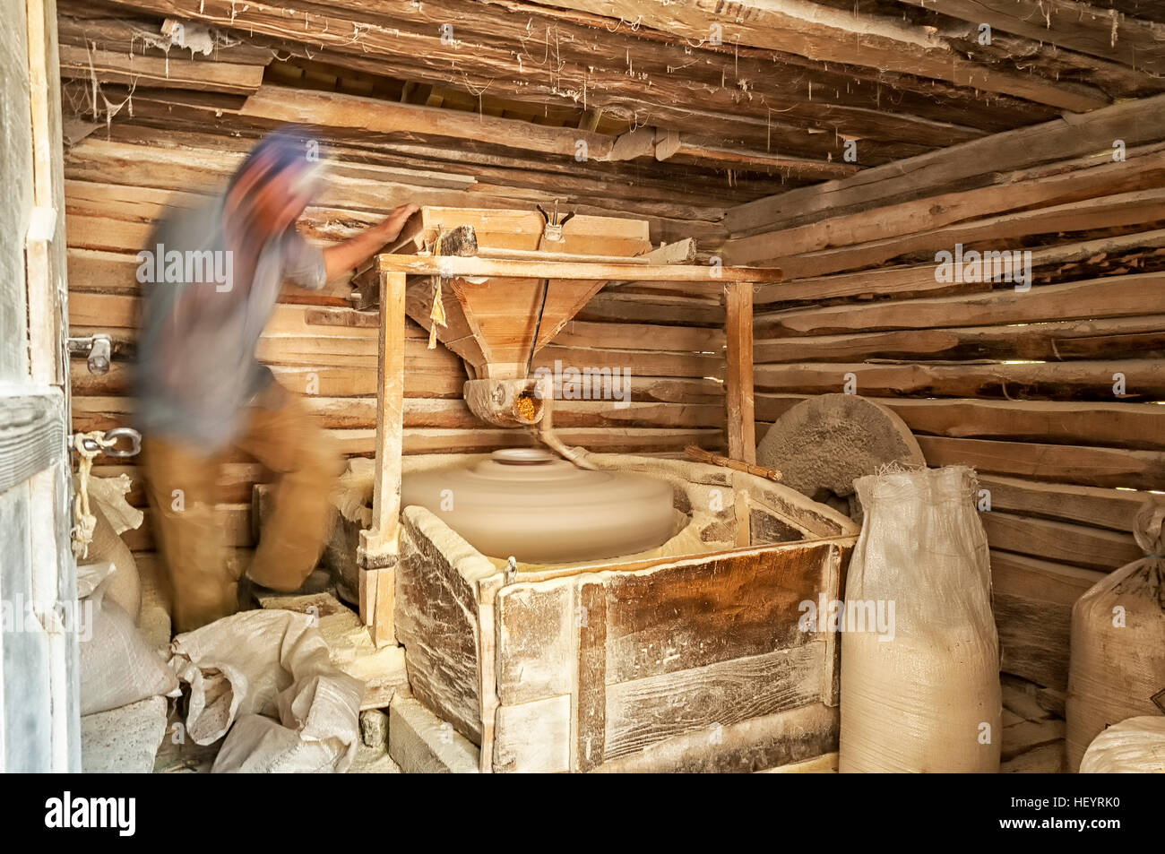 Man working in a small mill. Man making corn flour. Wooden water mill