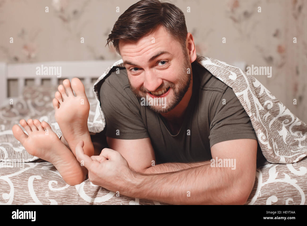 Playful man tickle woman's feet in bed. Stock Photo