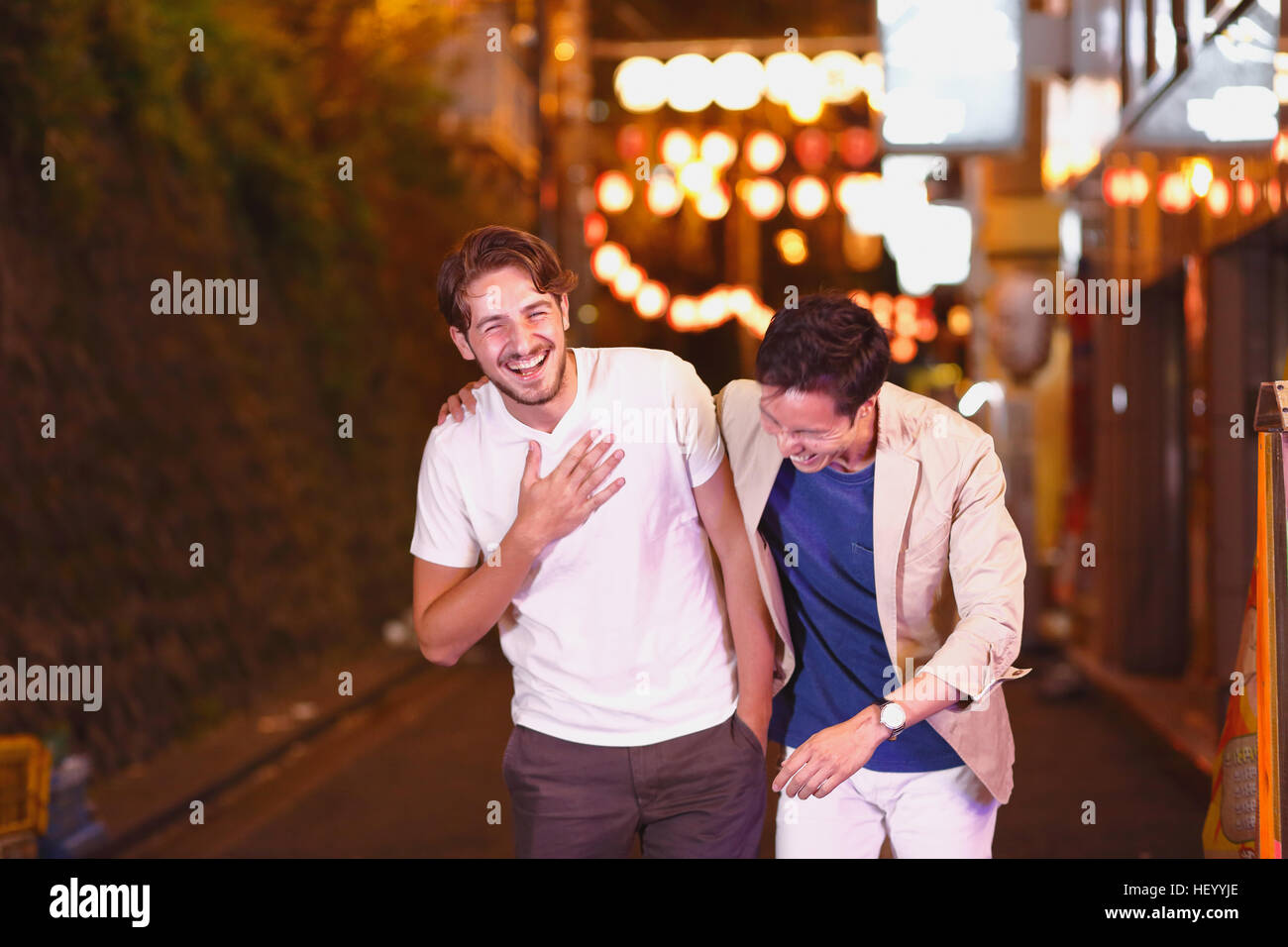 Caucasian man enjoying nightlife in Tokyo with Japanese friend, Japan Stock Photo