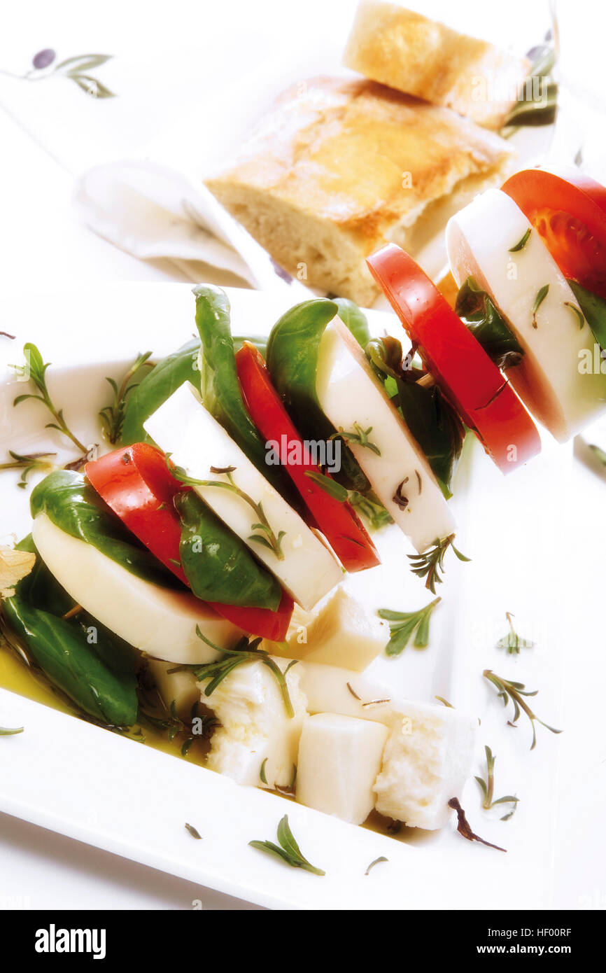 Skewered mozzarella with tomatoes, basil and herbs with baguette Stock Photo