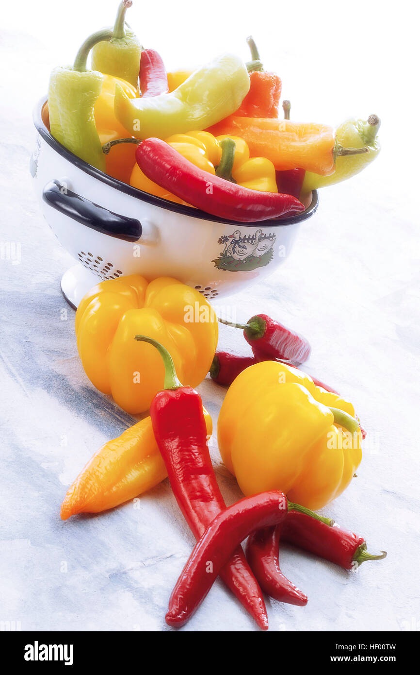 Yellow bell peppers with red chili peppers (Capsicum) and sieve, colander Stock Photo