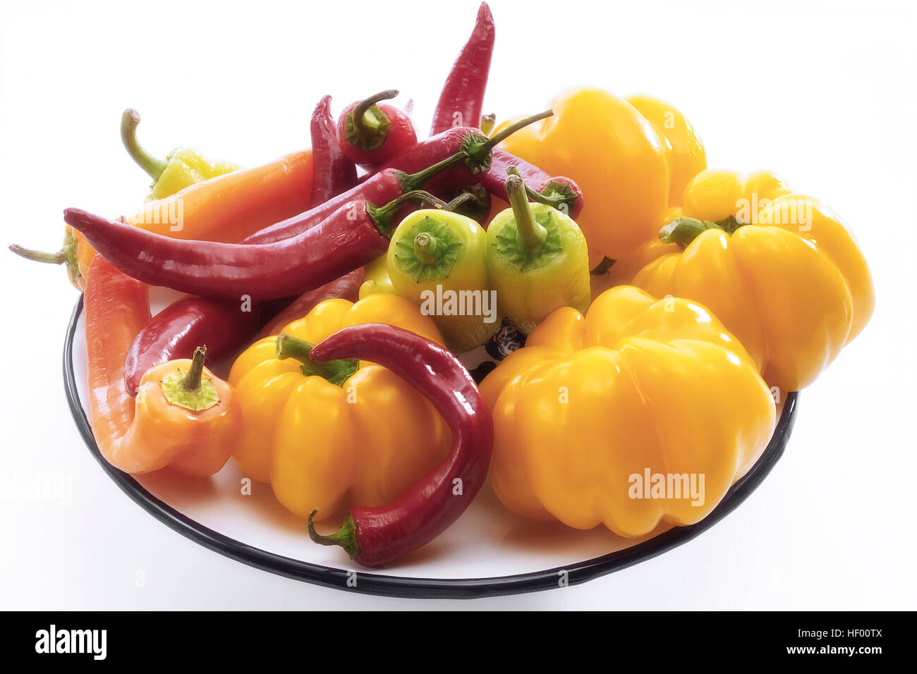 Yellow bell peppers with red and yellow chili peppers (Capsicum) on a plate Stock Photo