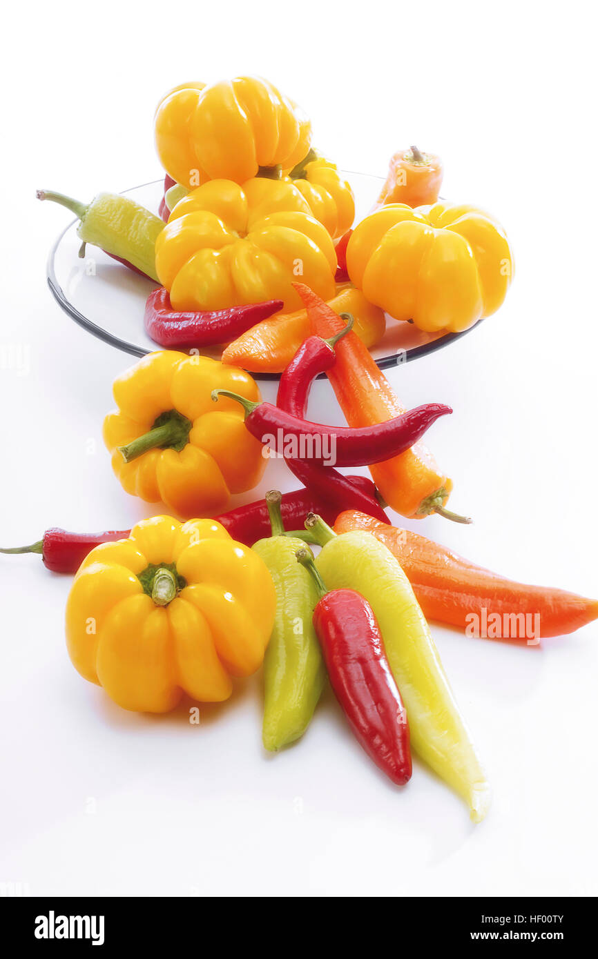 Yellow bell peppers with red and yellow chili peppers (Capsicum) on a plate Stock Photo