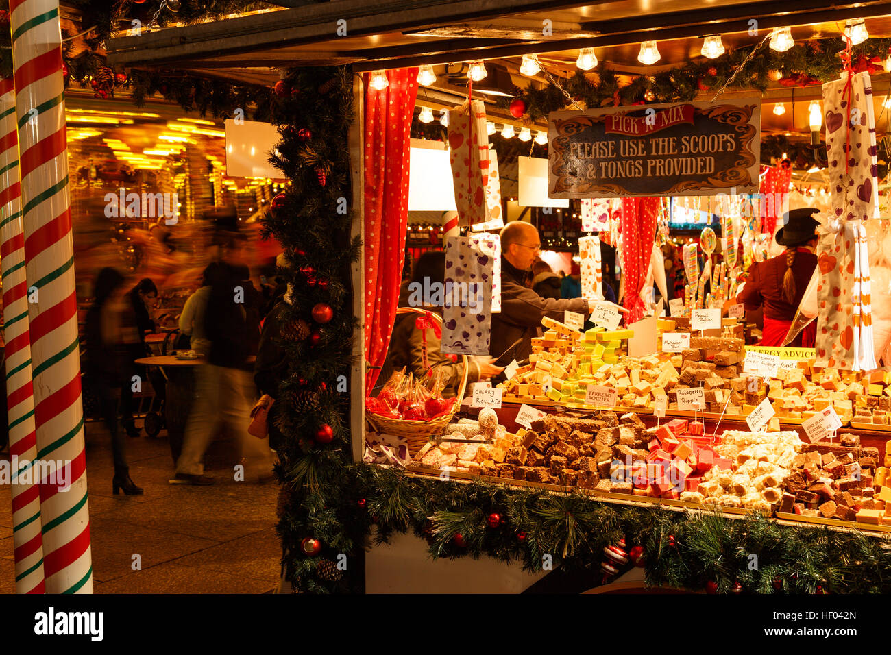 Man buying at sweet/candy stall at Nottingham Christmas market at night. In Nottingham, England