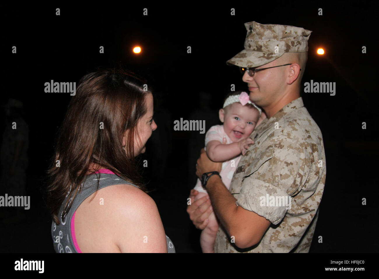 Lance Cpl. Brandon S. Hill, an air traffic control navigation aids technician with Marine Air Control Squadron 2, hugs his 5-month-old daughter Mackenzie while his wife Casey talks to him before leaving with Marine Air Communication Squadron 2 to the Aerial Point of Embarkation to fly to Afghanistan for a seven month deployment, Aug. 11. More than 200 Marines are heading out to Afghanistan for various missions under the command of Marine Air Control Group 28. The only squadron that falls under MACG-28 here in garrison that isn’t deploying with the group is Marine Unmanned Aerial Vehicle Squadr Stock Photo