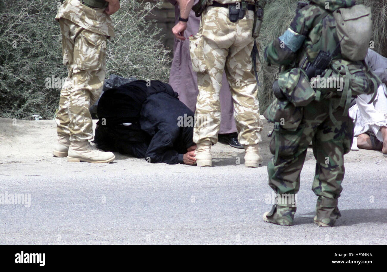 A local Iraqi citizen shows deference for an unidentified Royal Marine, as coalition forces arrive in the city of Umm Qasr, Iraq, during Operation IRAQI FREEDOM. Iraqi woman kisses British boots Stock Photo