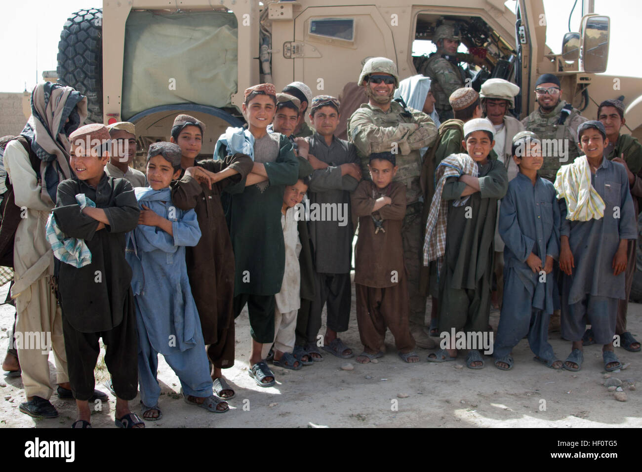 Ed, a linguist with Tactical Psychological Operations Team (TPT) 1377, supporting 1st Battalion, 7th Marine Regiment, Regimental Combat Team 6, poses with a group of local Afghan children during Operation Sangin Moshtarak Naweed in Sangin, Helmand province, Afghanistan May 18, 2012. Ed and Soldiers with TPT 1377 interacted with the local nationals to help build rapport. (U.S. Marine Corps photo by Sgt. Logan W. Pierce/Released) Operation Sangin Moshtarak Naweed 120518-M-EU691-037 Stock Photo