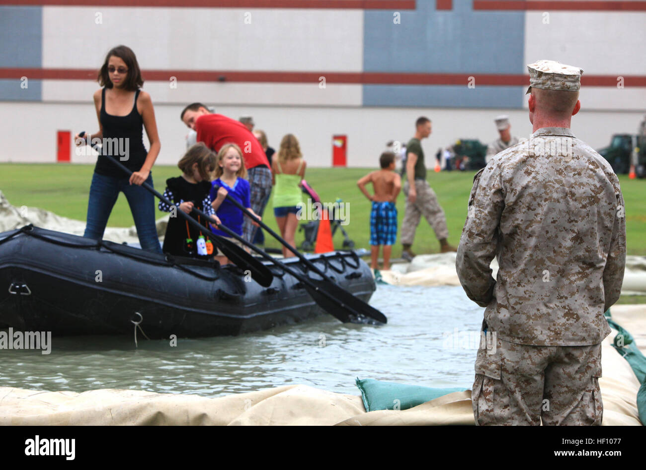 Cpl. John A. L. Silkey, a heavy equipment mechanic with 2nd Maintenance Battalion, 2nd Marine Logistics Group, watches over a group of visitors as they struggle to navigate their zodiac on a man-made pool set up for the battalion’s open house aboard Camp Lejeune, N.C., Sept. 19, 2012. Each of the battalion’s six companies set up stations for families and friends, which allowed them to experience some of the things their Marines do to support operations aboard the base. Marines open doors for families, friends 120919-M-ZB219-090 Stock Photo