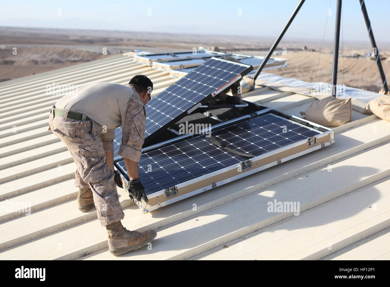 U.S. Marine Cpl. Moses E. Perez, a field wireman with Combat Logistics 15 installs new solar panels on Combat Outpost Shukvani, Helmand province, Afghanistan, Nov. 19, 2012. Perez installed the solar panels to provide power to radios, laptops, and computers in the event of power outages. (U.S. Marine Corps photo by Lance Cpl. Alexander Quiles/Released) Solar Panel installment 121119-M-SF473-009 Stock Photo