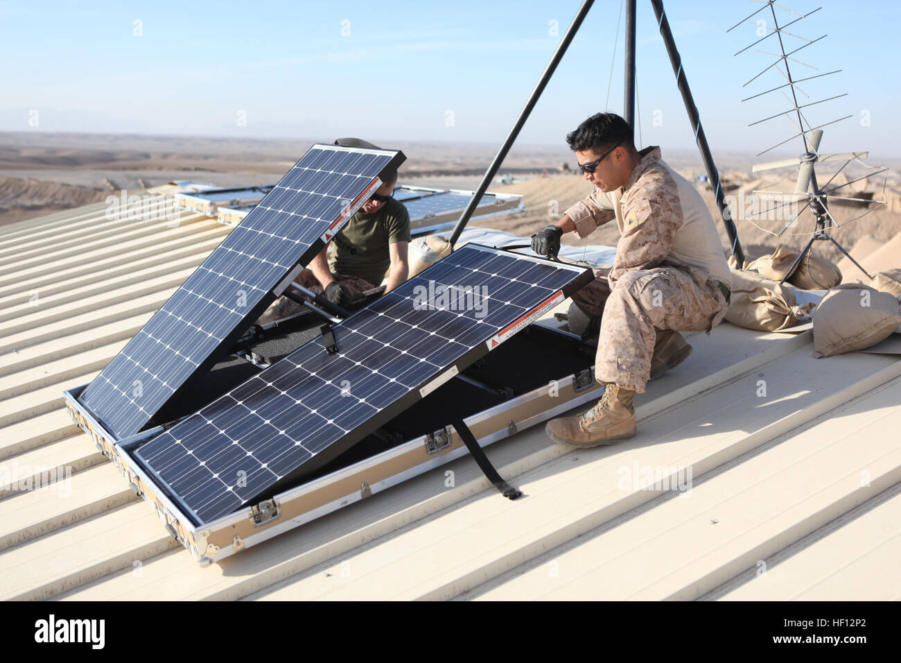 U.S. Marine Corps Cpl. Robert G. Sutton, left, and Cpl. Moses E. Perez, field wireman with Combat Logistics Regiment 15 install new solar panels on Combat Outpost Shukvani, Helmand province, Afghanistan, Nov. 19, 2012. Sutton and Perez installed the solar panels to provide power to radios, laptops, and computers in the event of power outages.(U.S. Marine Corps photo by Lance Cpl. Alexander Quiles/Released) Solar Panel installment 121119-M-SF473-010 Stock Photo