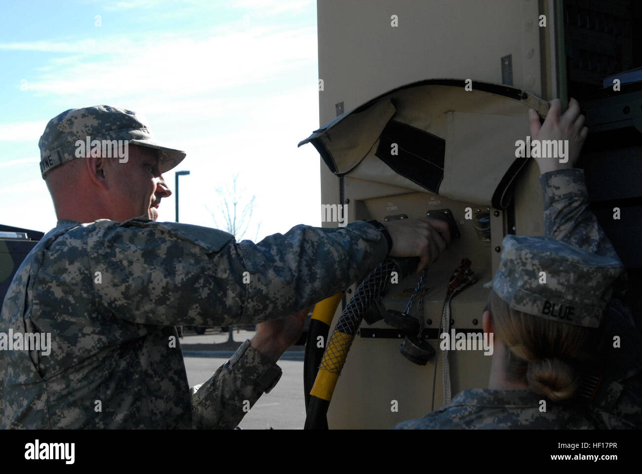 North Carolina National Guard Army Spc. Erik Van Dyne (left) connects the generator power cord as Spc. Megan Blue holds up the closure flap during the 295th Signal Network Support Company's preparation for annual training, April 13. Van Dyne and Blue manned the Joint Network Node during the training, making sure the Internet and phones received connection. Van Dyne entered the military about three years ago without any computer knowledge and was told to enter this military occupation based on his entrance test scores. He said the training he received helped get an information technician positi Stock Photo