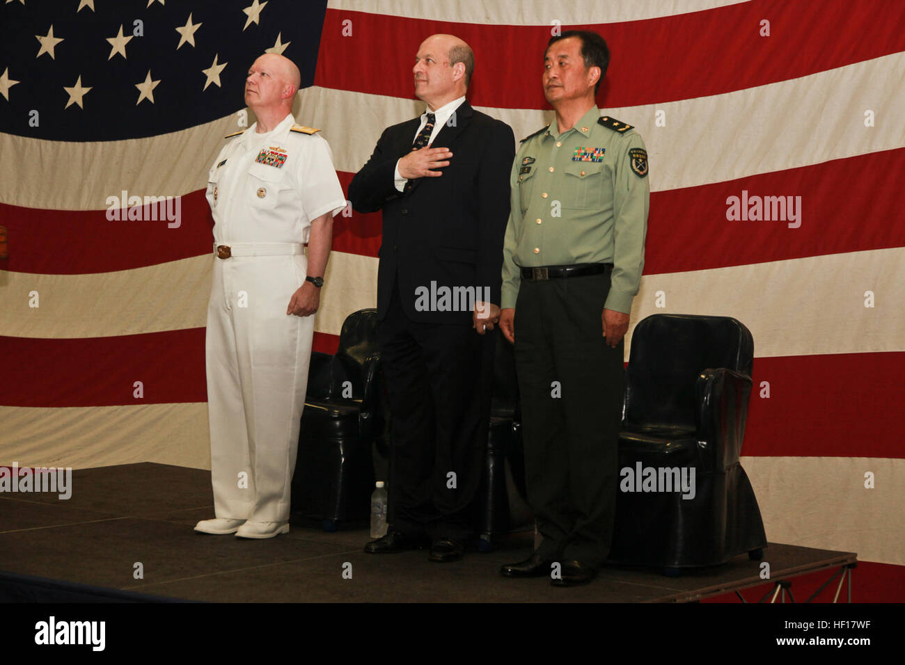 (Left to right) Rear Adm. Jeffrey A. Harley, commander, Expeditionary Strike Group Seven; Matt J. Matthews, acting U.S. consul general, Hong Kong; Maj. Gen. Dong Chao, deputy commander, People’s Liberation Army - Garrison Hong Kong; render honors during the playing of the national anthem during a reception held in the hangar bay of USS Peleliu after the ships of the ARG pulled in to Hong Kong, April 15. The reception was held to welcome guests and foreign dignitaries to the ship and gave senior leaders the opportunity to expand on personal and professional relationships. The Hong Kong port vis Stock Photo