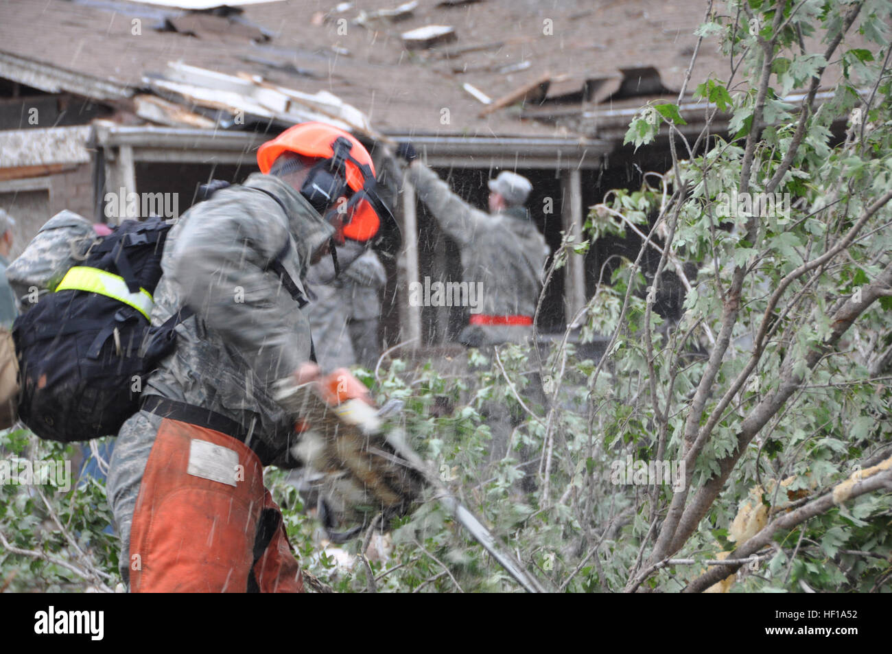A military member cuts trees that were brought down on homes after a tornado hit the town of Moore, Okla. May 20, 2013.  (U.S. Air Force photo by Maj. Jon Quinlan) Oklahoma recovers after devastating EF-5 tornado (8781357849) Stock Photo