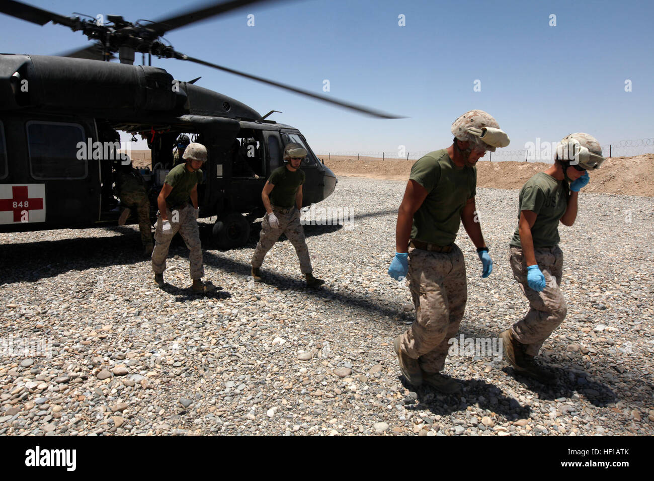 U.S. Marines with Surgical Platoon, Combat Logistics Company, Combat Logistics Regiment 2, walk away from a UH-60 Black Hawk after carrying an injured Afghan National Army Soldier at Combat Outpost Shukvani, Helmand province, Afghanistan, June 8, 2013. The Marines are part of the shock trauma platoon, responsible for providing medical care to casualties brought to Shukvani. (U.S. Marine Corps photo by Sgt. Gabriela Garcia/Released) STP aides an injured Afghan 130608-M-SA716-293 Stock Photo