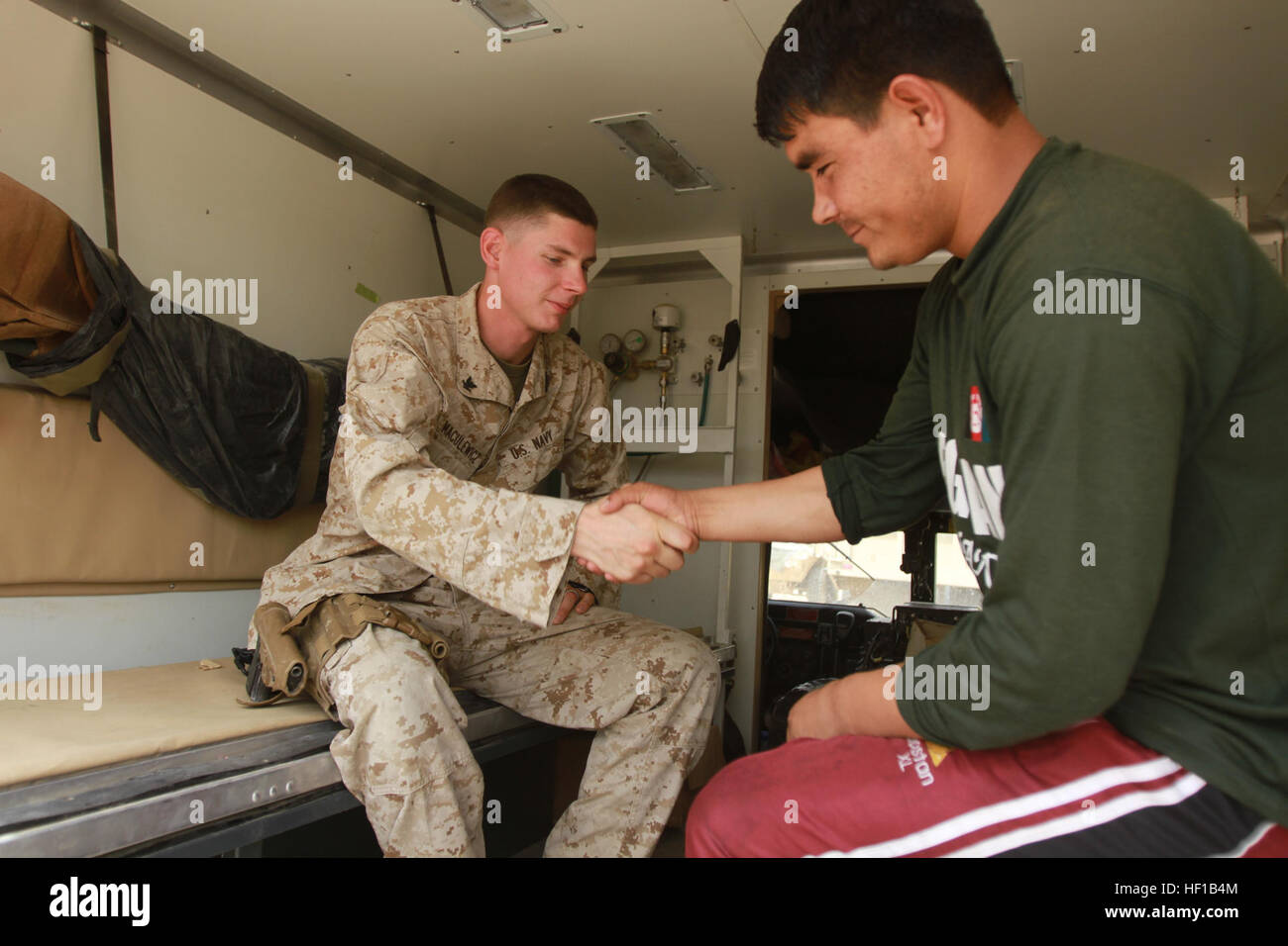 U.S. Navy Petty Officer 3rd Class Stanley Maculewicz, a corpsman with the Afghan National Army 215th Corps Mobile Strike Force Security Force Assistance Advisor Team (SFAAT), and ANA Staff Sgt. Abdul Malik shake each other's hands at Camp Shorabak, Helmand Province, Afghanistan, June 15. Maculewicz provided life-saving measures to Malik, a MSF medic, during a recent operation in Sangin, where Afghan National Security Forces cleared Taliban from one of Afghanistan's more volatile districts. Malik and another ANA medic were en route to pick up a fallen soldier when Malik was wounded by an enemy  Stock Photo