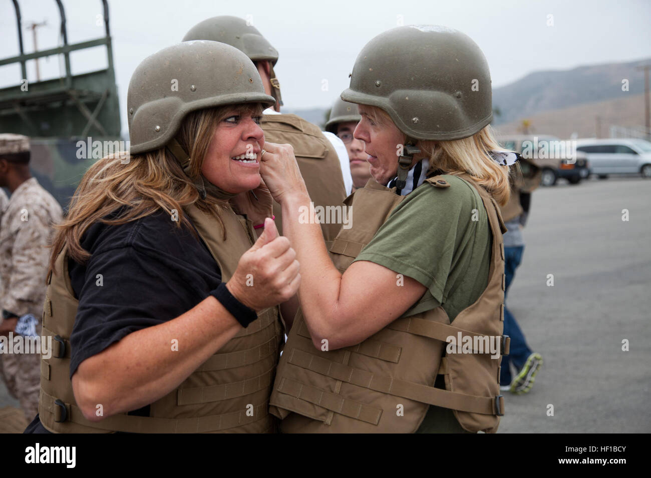 Monica Russell, right, wife of U.S. Marine Corps Col. Joseph Russell, commanding officer of Headquarters Battalion (HQBN), 1st Marine Division (1st MARDIV), secures a kevlar helmet on Janet Fliegel, left, wife of Sgt. Maj. Daniel Fliegel, Battalion Sgt. Maj., during HQBN's Jane Wayne day aboard Camp Pendleton, Calif., June 22, 2013. Jane Wayne Day is an opportunity for family and friends of service members to participate in Marine Corps training, while strengthening family readiness through team building. (U.S. Marine Corps photo by Pfc. Adrianna Stalker, 1st Marine Division/Released) GI Joe a Stock Photo