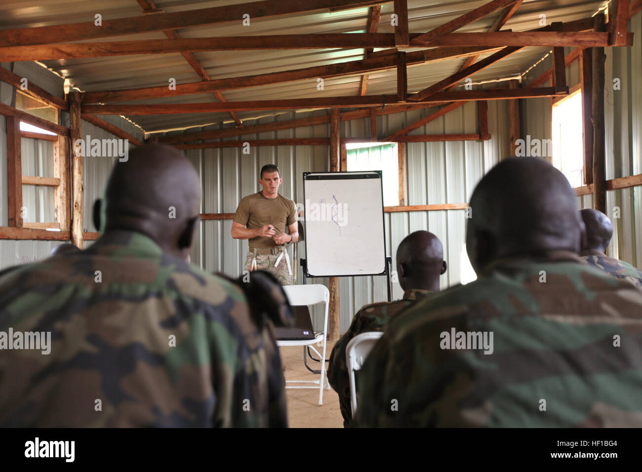 U.S. Navy Explosive Ordinance Disposal 1st Class Mark Balliet, an EOD technician with Combined Joint Task Force-Horn of Africa (CJTF-HOA), explains counter-IED tactics to a group of Uganda People’s Defense Force (UPDF) soldiers at the Peace Support Operations Training Center-Singo in Kakola, Uganda, June 24, 2013. Balliet and Marines and Sailors with Special-Purpose Marine Air-Ground Task Force (MAGTF) Africa recently completed a logistics focused engagement with UPDF soldiers who will deploy to Somalia later this year. Since deploying in January, Special-Purpose MAGTF Africa has trained more  Stock Photo