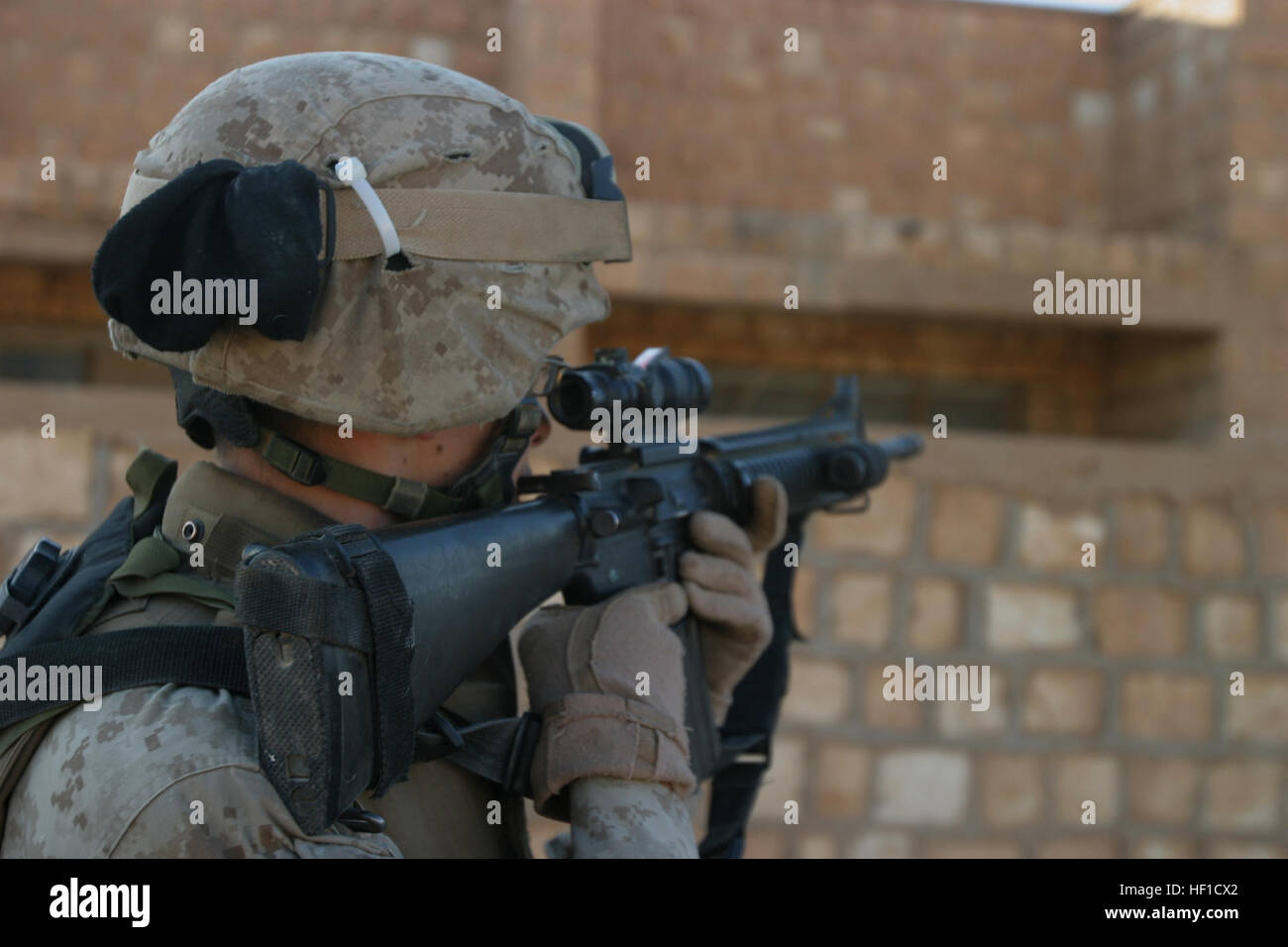 U.S. Marine Lance Cpl. Jeremy P. Cook from 4th Squad, 1st Platoon (1st Plt), Alpha Battery, 1st Battalion, 12th Marines (1/12), Task Force Military Police (TFMP) peers through the scope of his M4 rifle for abnormal activity during a foot patrol through Al Waleed, Iraq. 1st Plt develops community relations through foot patrols and provide security for the town by the Iraq-Syria border. 1/12 TFMP is deployed with Multi National Forces-West in support of Operation Iraqi Freedom in the Al Anbar province of Iraq to develop Iraqi Security Forces, facilitate the development of official rule of law th Stock Photo