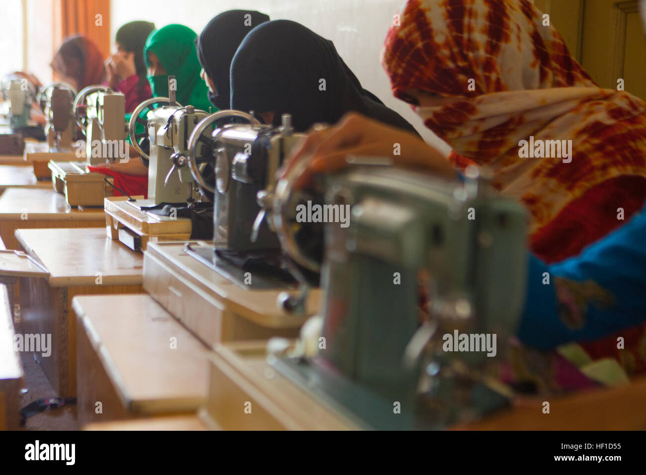 A group of Afghan women use sewing machines to make clothing at the
