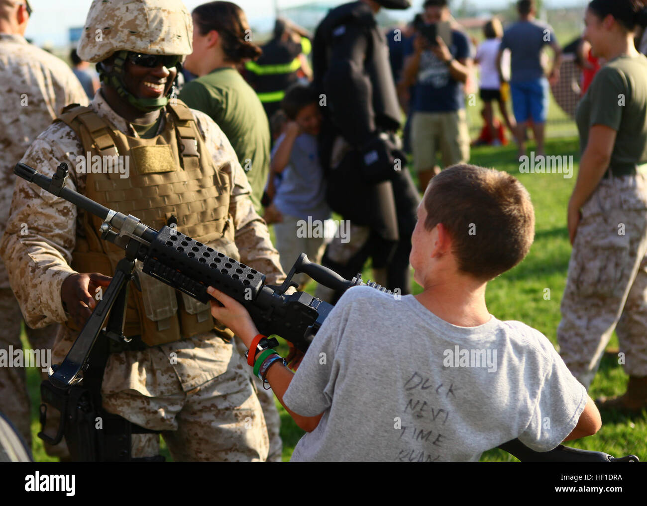 Gunnery Sgt. Octavius Shivers, the logistics chief with Special-Purpose Marine Air-Ground Task Force Africa 13, smiles as he shows off the M240G machine gun to a young-boy during the National Night Out event aboard Naval Air Station Sigonella, Italy, Aug. 6, 2013.  Marines and sailors with Special-Purpose MAGTF Africa participated in the event with a static display of weapons, both lethal and non-lethal. Special-Purpose MAGTF Africa continues to build relationships with the community while simultaneously strengthening U.S. Africa Command and U.S. Marine Corps Forces Africa's ability to assist  Stock Photo